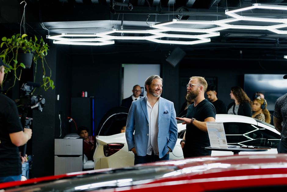A luxury car event with attendees and videographers in a stylish Los Angeles showroom.